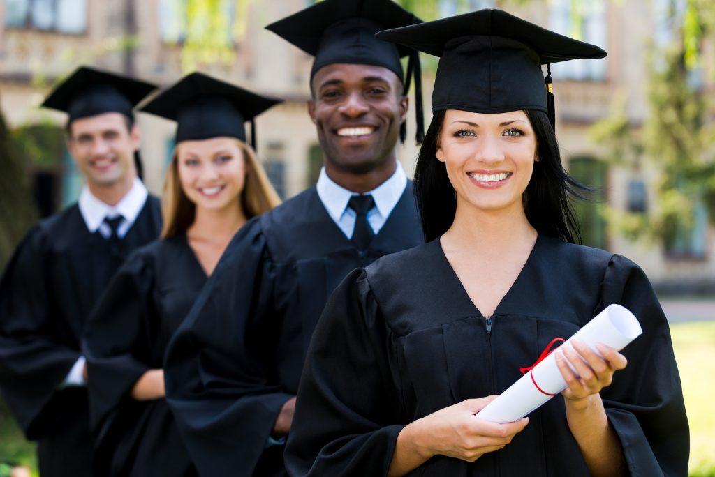 Happy graduates. Four college graduates standing in a row and smiling