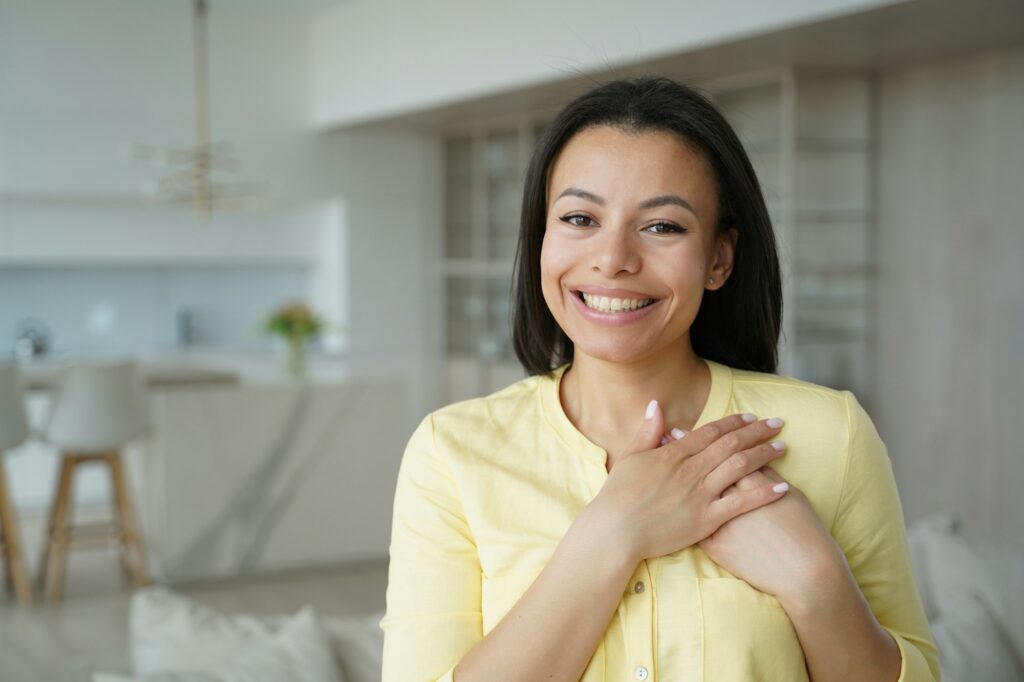 Thankful female keep hands close to heart, feel gratitude, appreciation happy with good deed at home